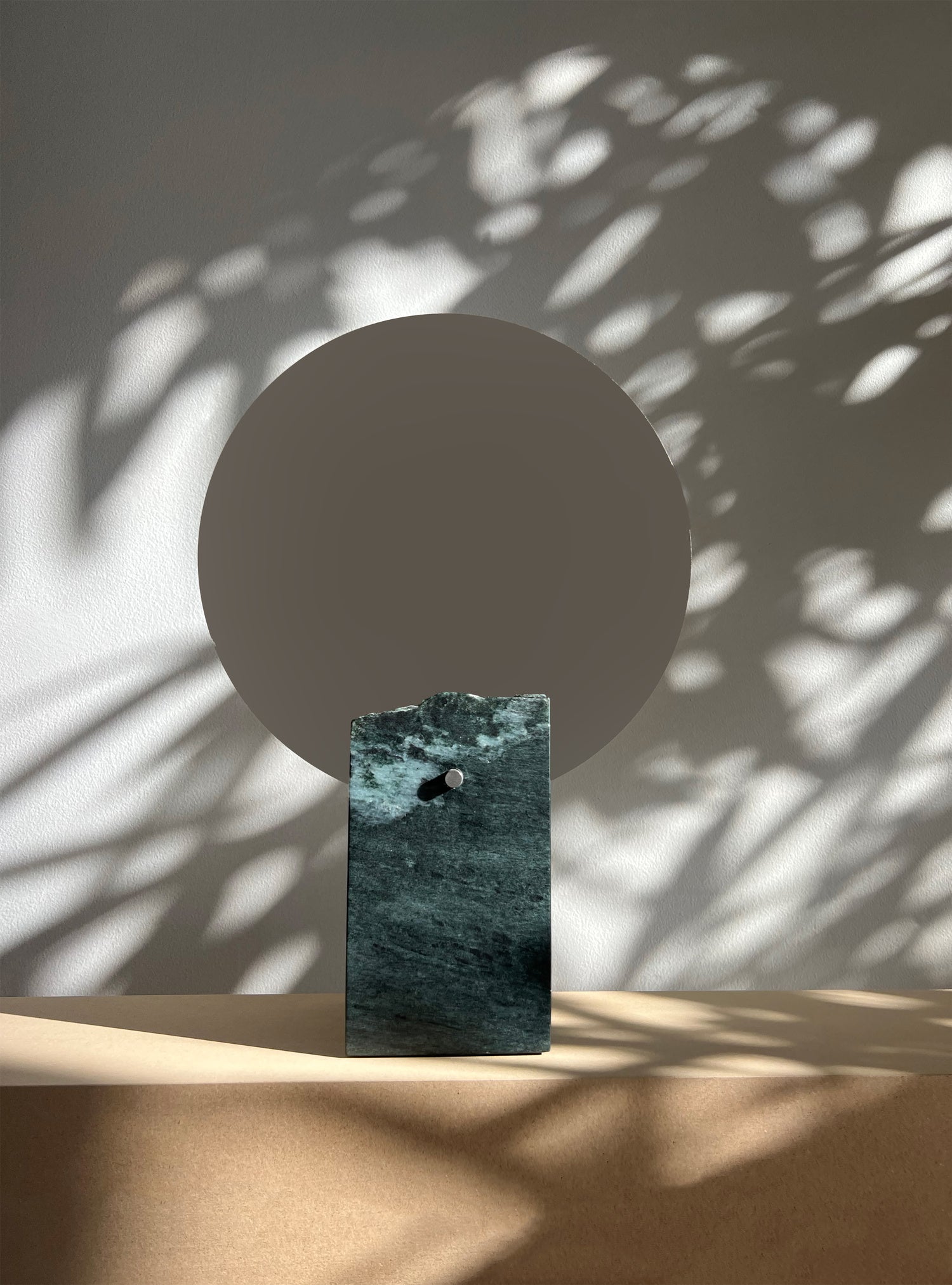 Decorative object with a circular top and rectangular base on a neutral background