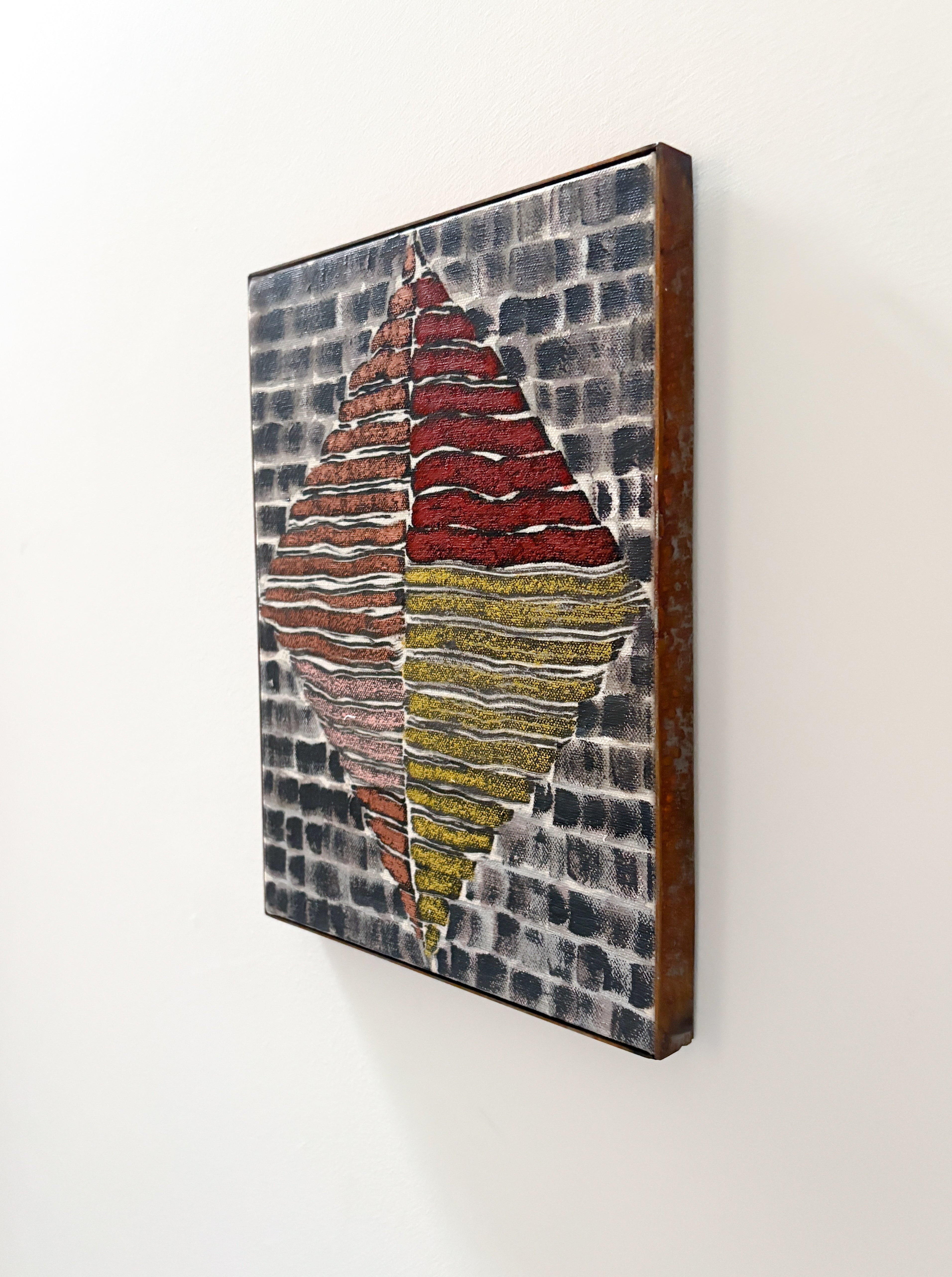 Abstract art piece with red, yellow, and gray colors on a white wall