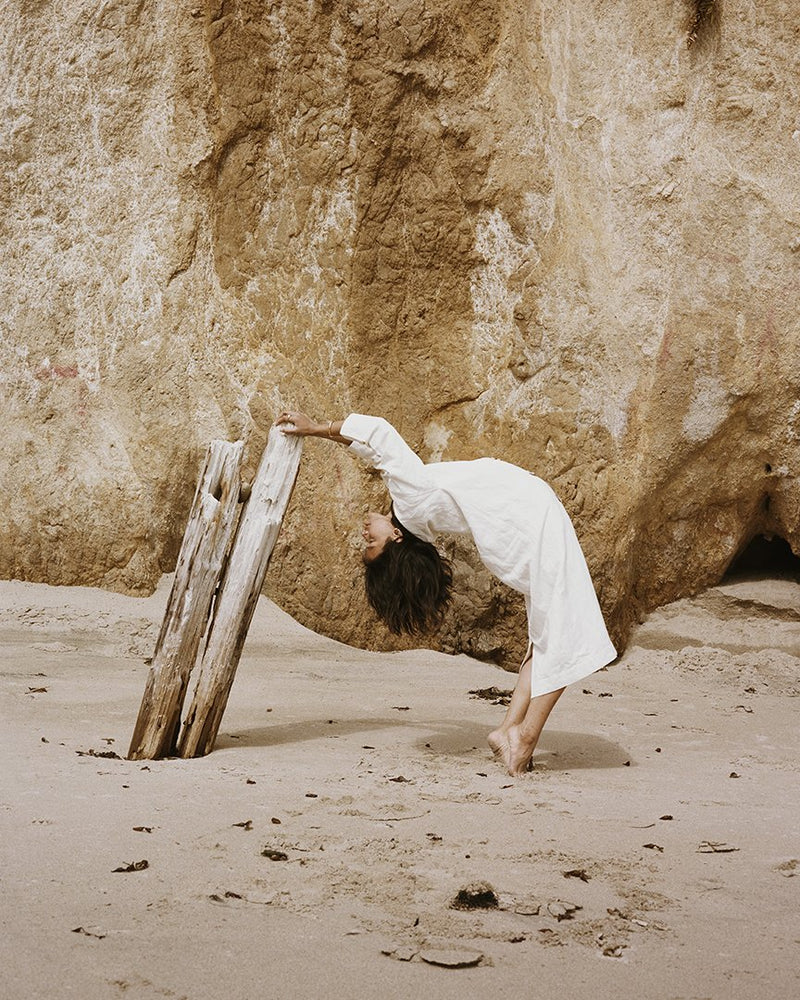 Woman leans backward and grabs onto driftwood.