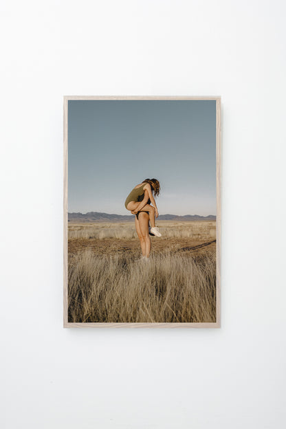 Person holding another person in a dry field, framed wall.