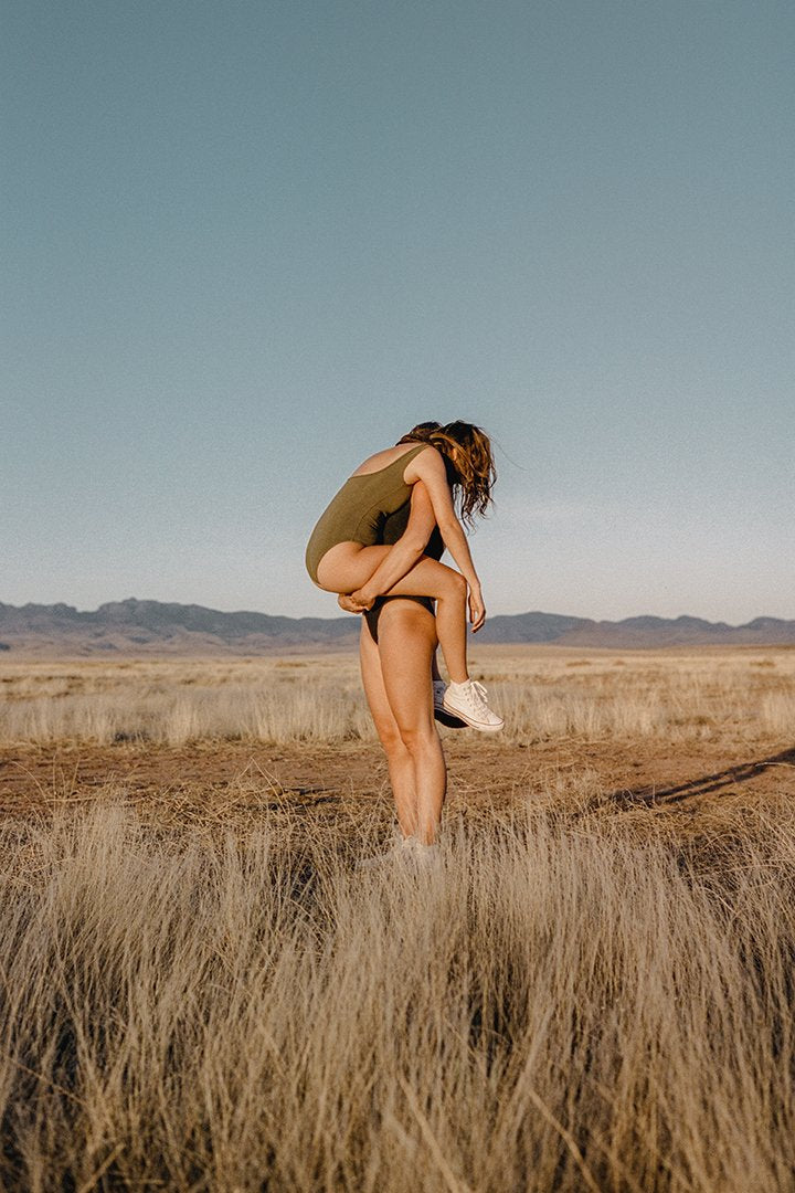 Person holding another person in a dry field.