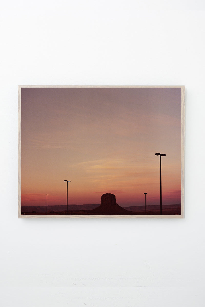 Rock formation extending from the ground at sunset, framed on white wall.