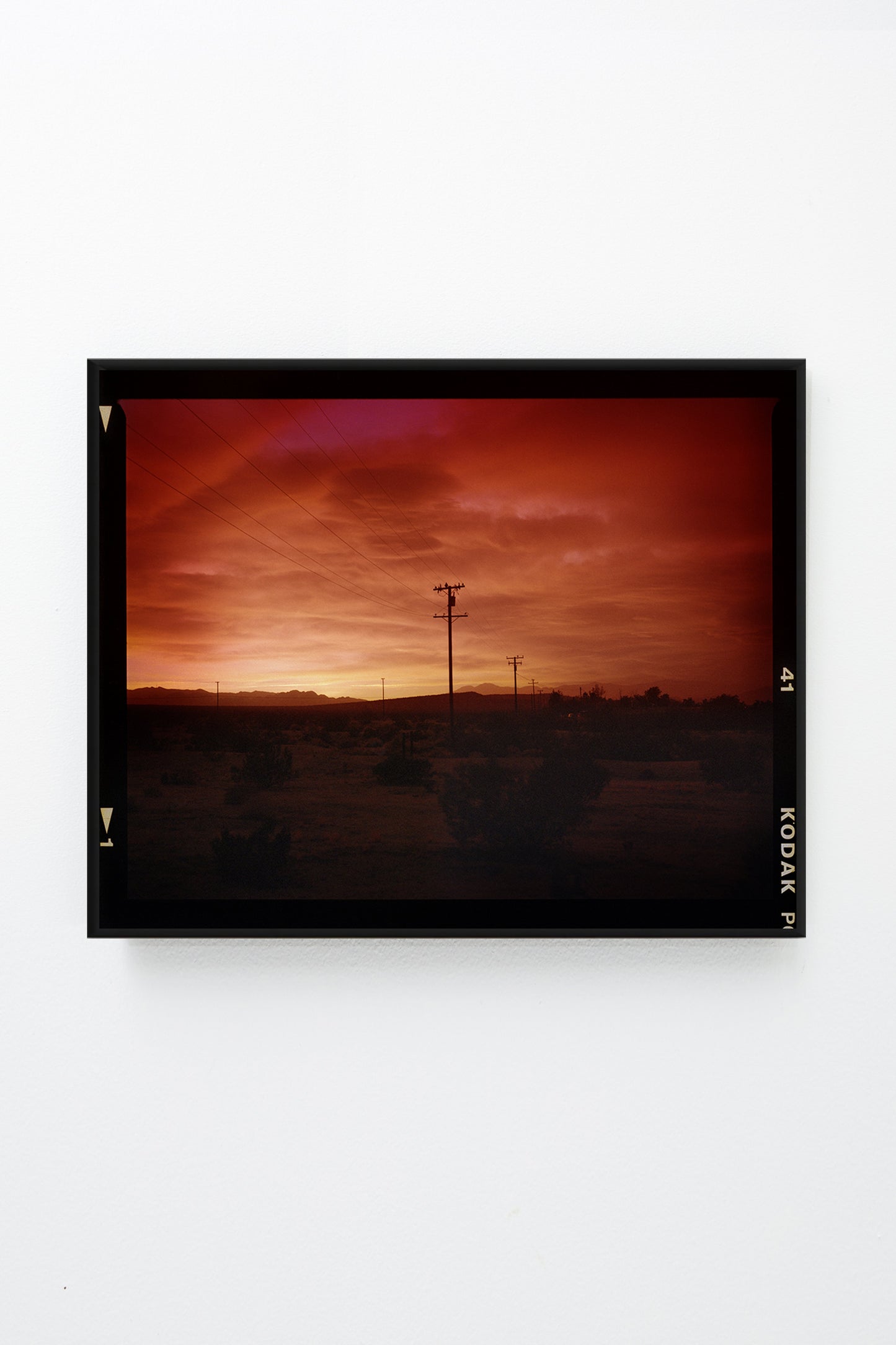 Red sky over desert landscape with telephone poles, framed.