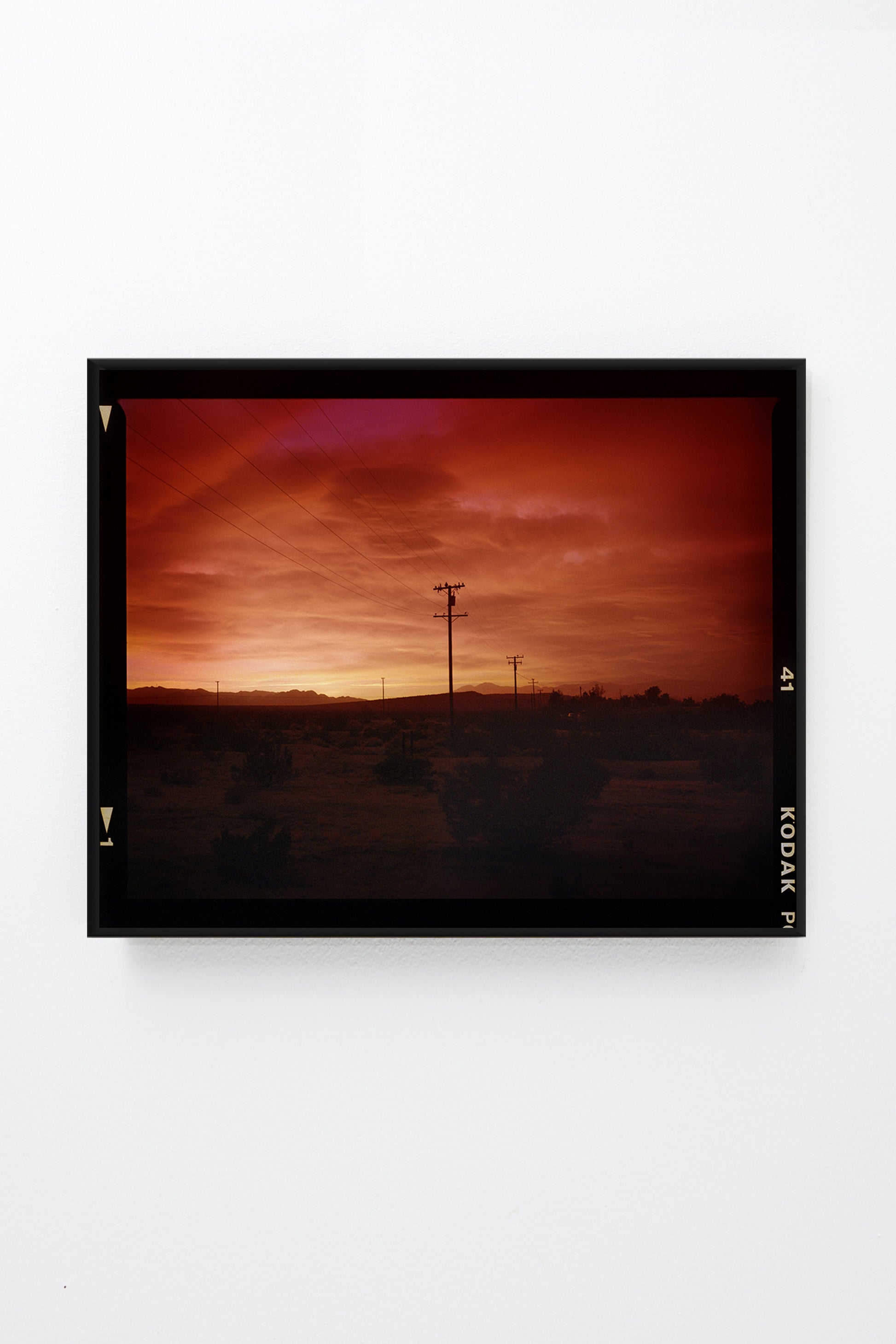 Red sky over desert landscape with telephone poles, framed.