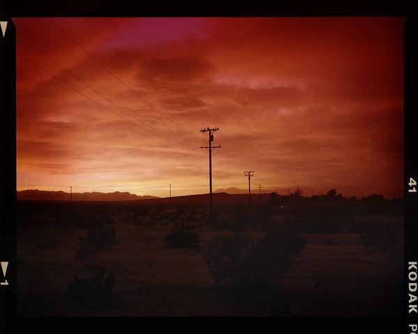 Red sky over desert landscape with telephone poles, unframed.