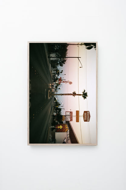 "Lost Vegas" (Street lined with casino and motel signs, cars, and palm trees), framed.