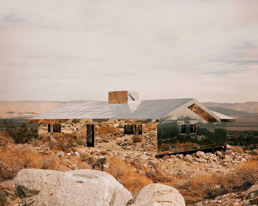 House made of mirrors in a rocky, mountainous landscape.