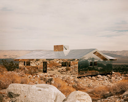 House made of mirrors in a rocky, mountainous landscape.