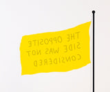 Yellow flag on black pole, text reads "THE OPPOSITE SIDE WAS NOT CONSIDERED"
