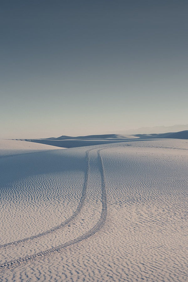 Vast desert landscape with tire tracks.